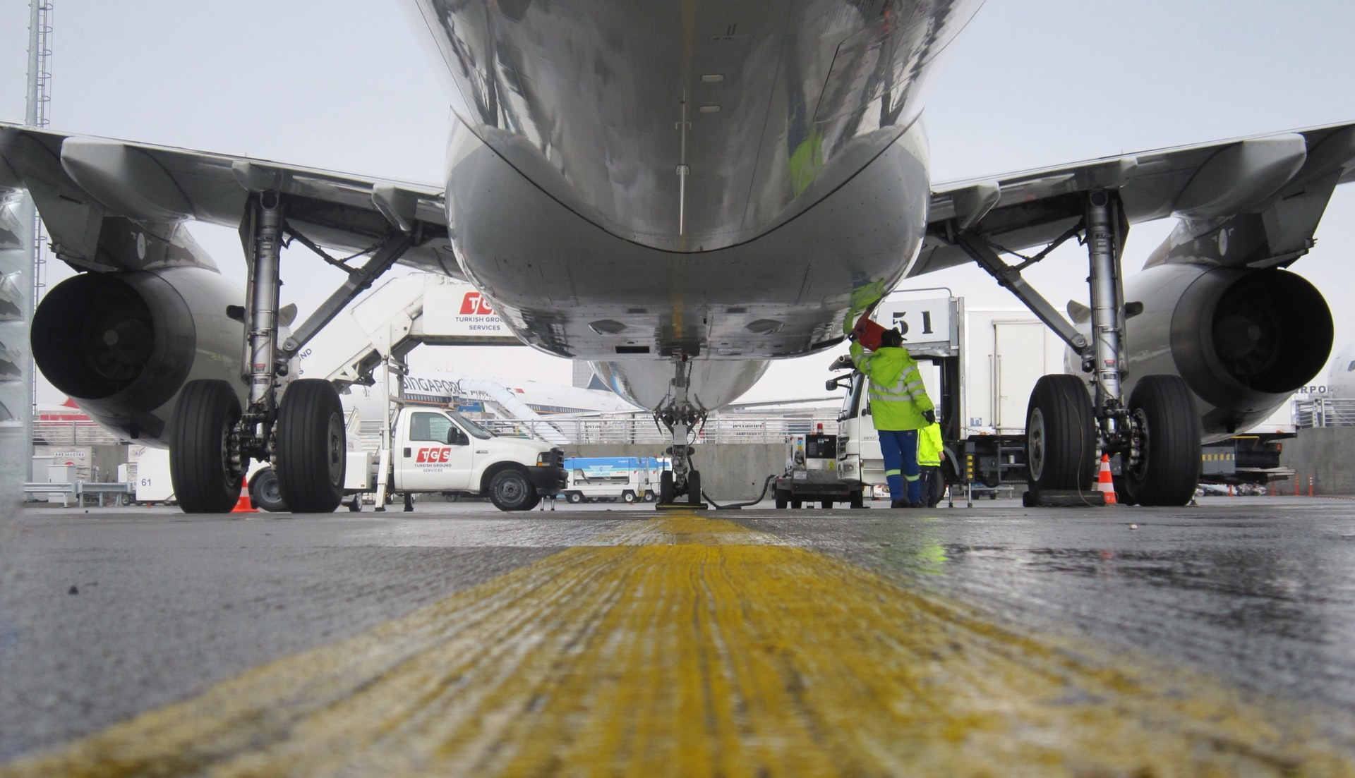 Engineers performing aircraft line maintenance on an airplane stationed outdoors.