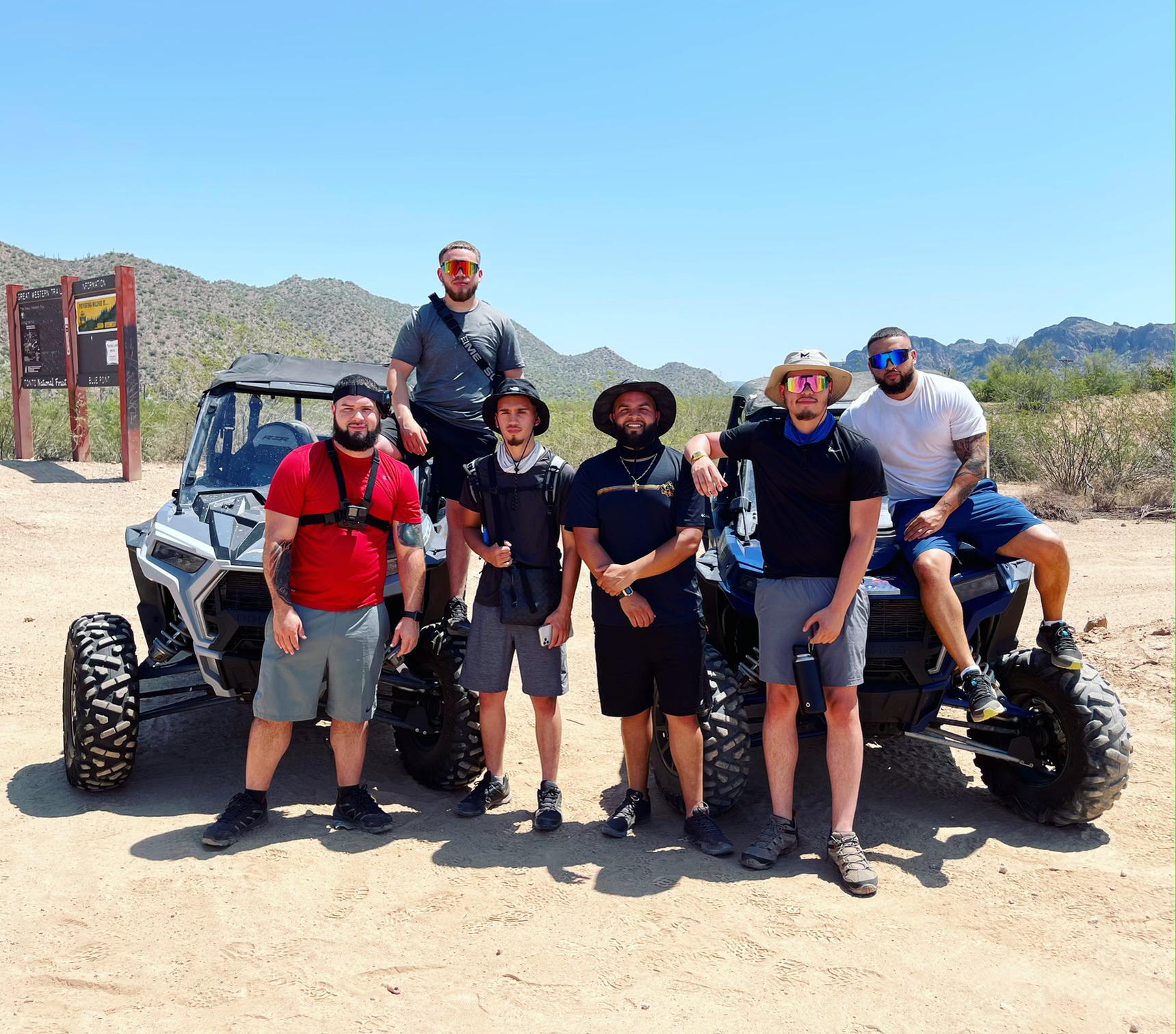 A group of people riding Polaris RZR UTVs in the Arizona desert