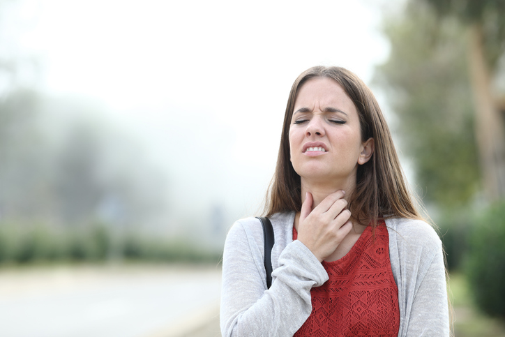 An image of a woman in pain with a seasonal sore throat. 