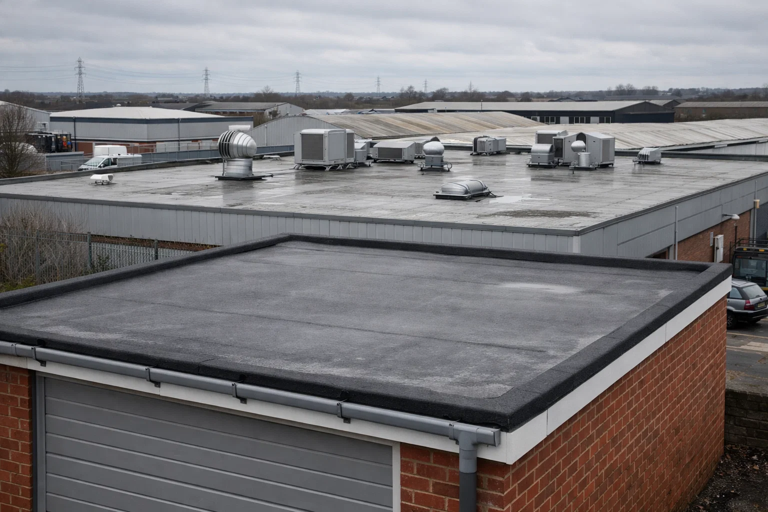Domestic garage flat roof and larger commercial flat roof building in Bolton industrial area.