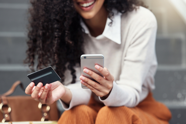 Pretty young woman holding her cell phone and credit card. 