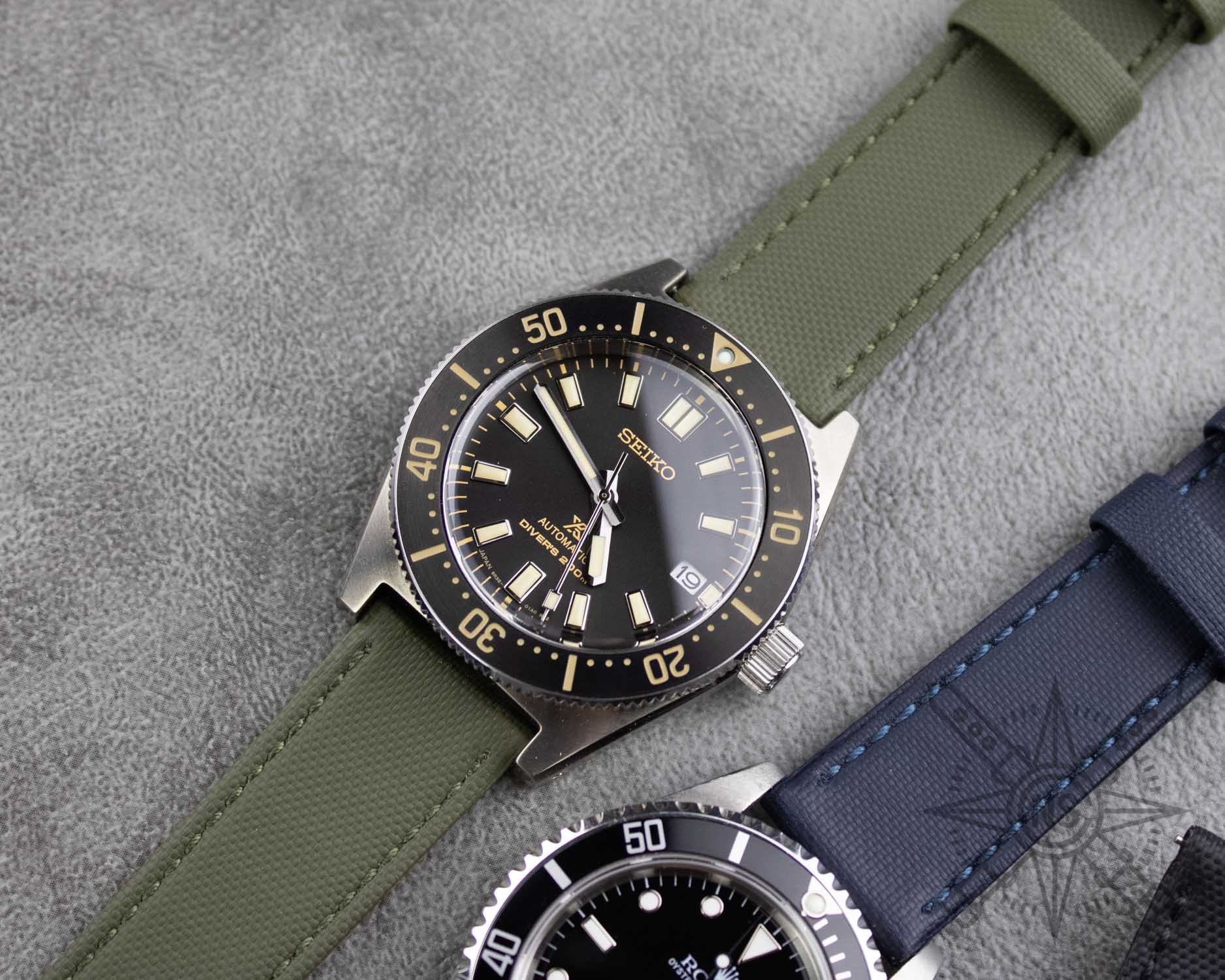A green sailcloth watch strap displayed elegantly against a neutral background.