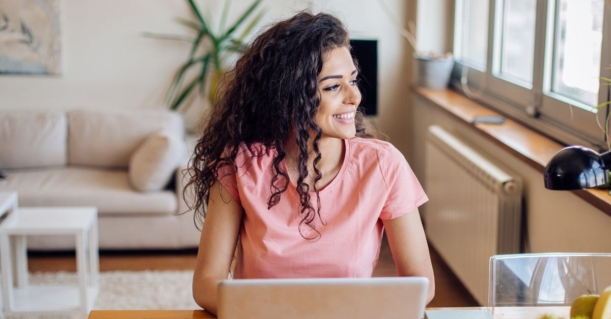 Happy OnlyFans creator using a laptop to understand federal excise tax obligations from home.