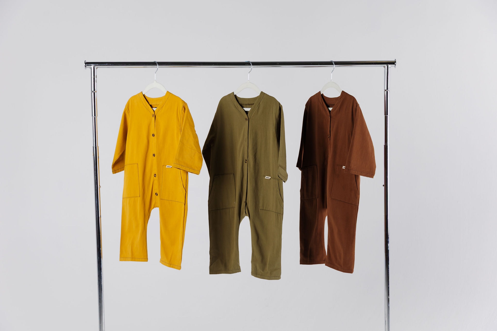 Wardrobe Kids Clothes classics. The off beat overalls available in Pistachio, Honeycomb and Chocolate | Overalls hanging on a rack.
