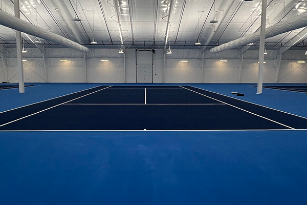 Indoor tennis court resurfacing project showing a clean, smooth surface designed to enhance playability.