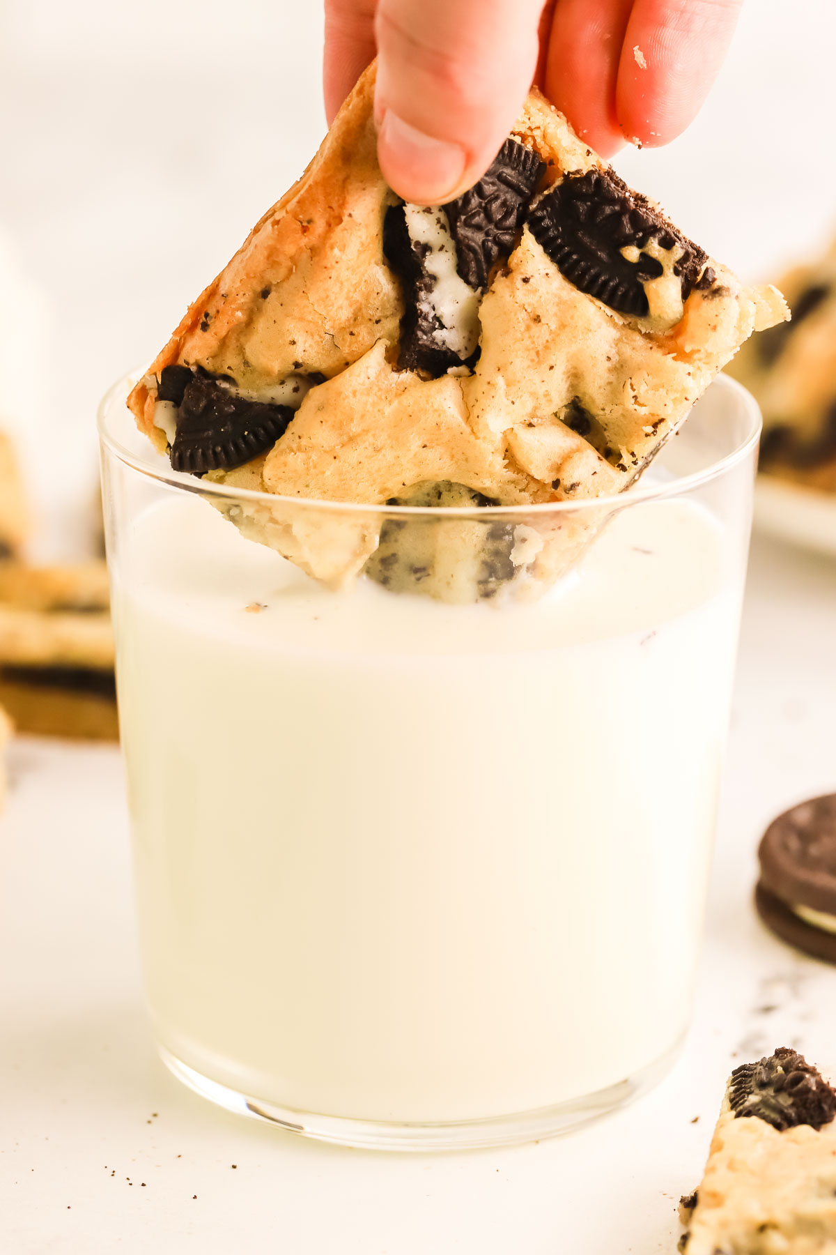 Oreo blondie being dunked into a glass of milk