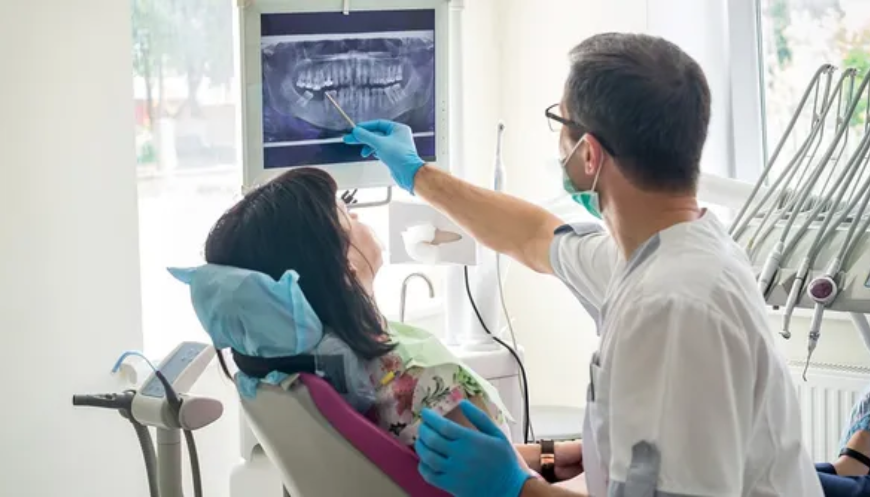 Rotfylling Pris: Hva Betaler Du Egentlig For? (Og Er Det Verdt Det?) 15 Tannlege forklarer røntgenbilde av pasientens tenner på skjerm under konsultasjon i moderne tannlegekontor.