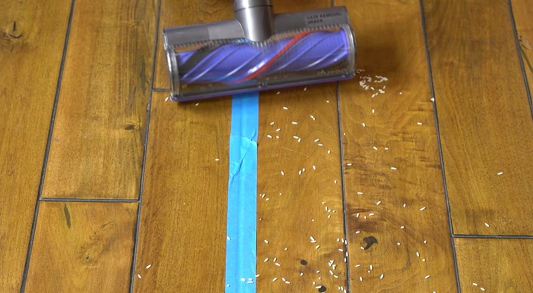 Dyson V8 cordless vacuum picking up rice on hardwood