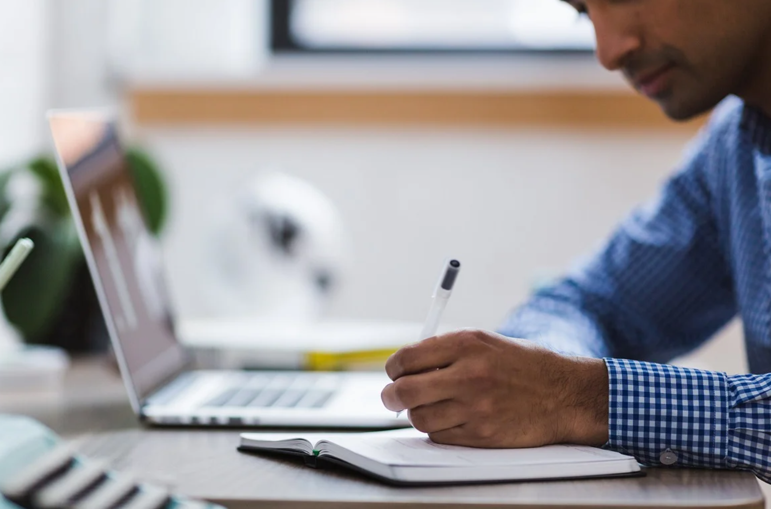 Man taking notes in front of a laptop