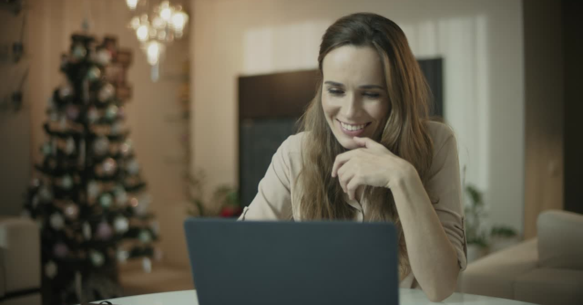 A relaxed woman working on her laptop at home, reviewing her federal total tax liability during the holidays.