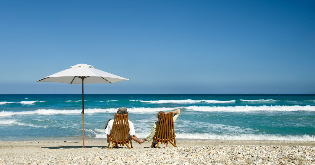 Couple relaxing in beach chairs under an umbrella facing the ocean on Long Beach Island.