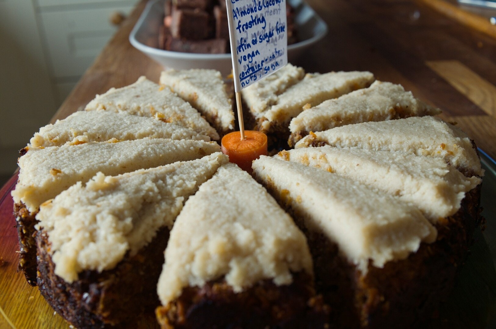 A beautifully decorated carrot cake with a sign placed on it.