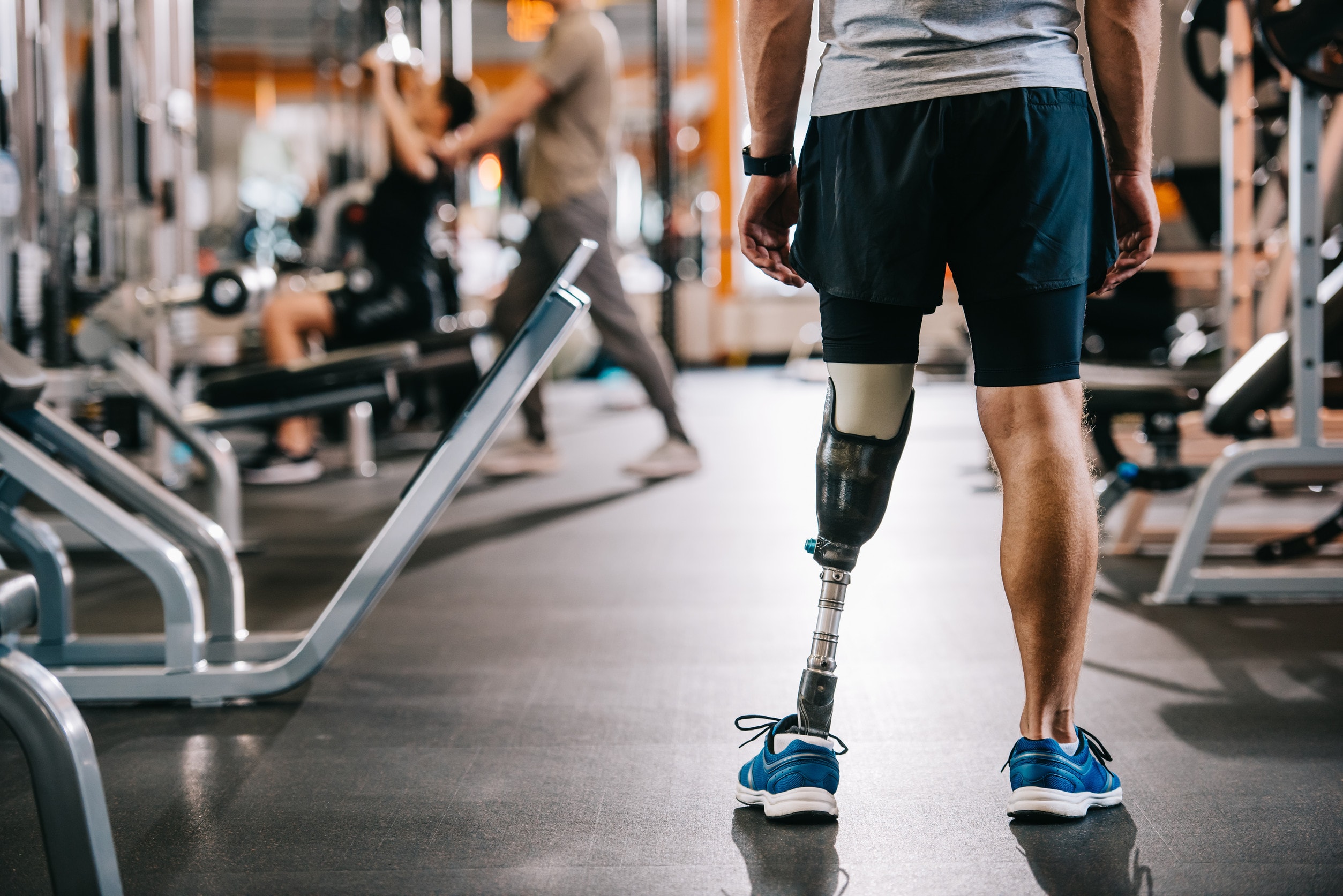 An amputee stands in a gymnasium facing the equipment