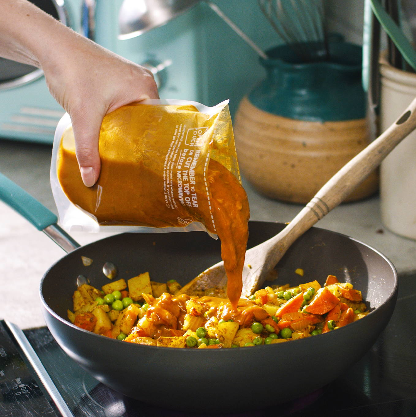 A person meal prepping with Proper Good's Spiced Pumpkin Soup and chopped veggies