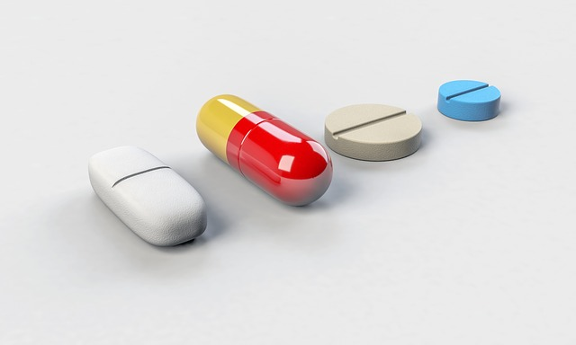 An image of a row of medications in pill, tablet, or capsule form on a table. 