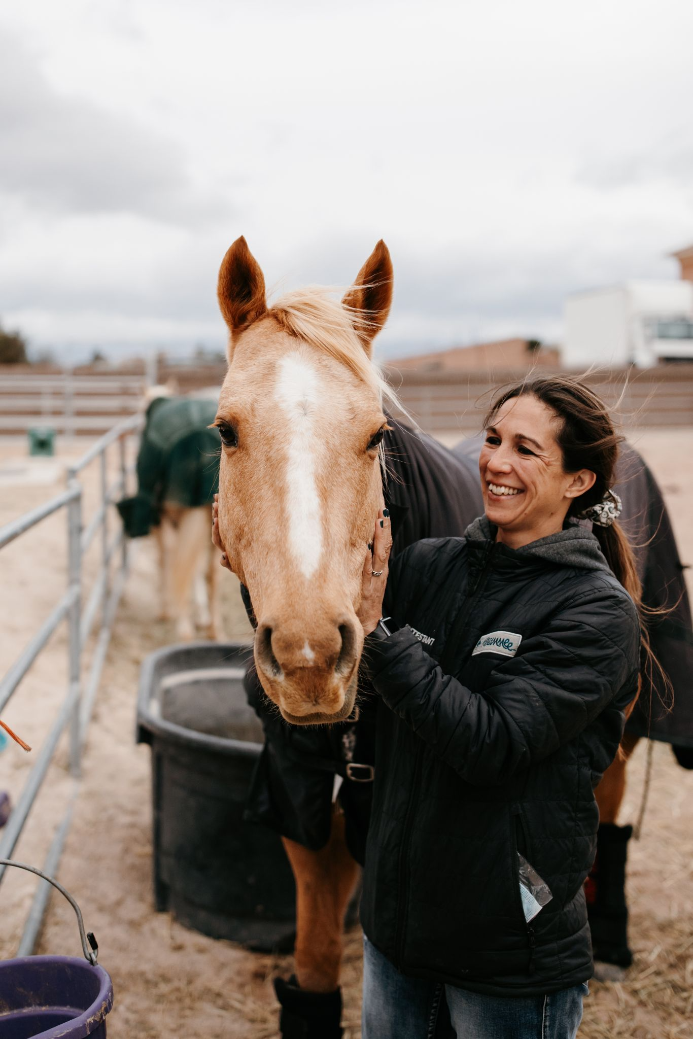 Lady holding a horse's mane and smiling at the horse