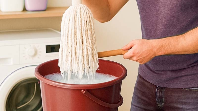 Man dipping mop head in bucket