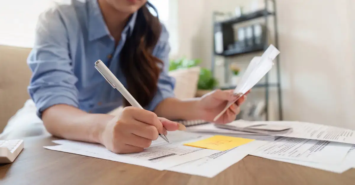 Woman reviewing IRS back taxes, unpaid tax bills, and financial records at her home office.