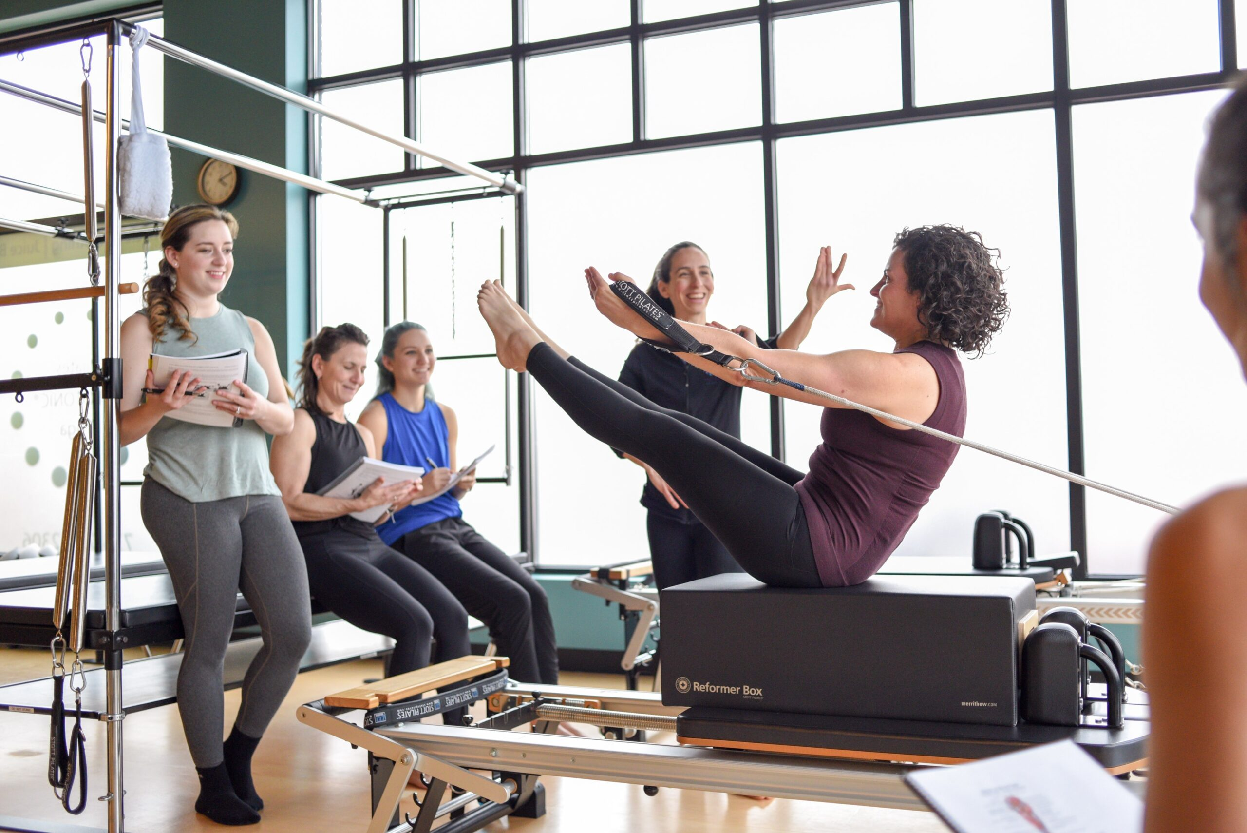 A woman teaching a pilates class with a group of people in the background