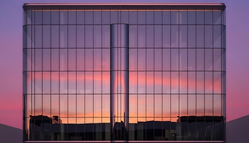 Modern glass building facade reflecting sunset colors