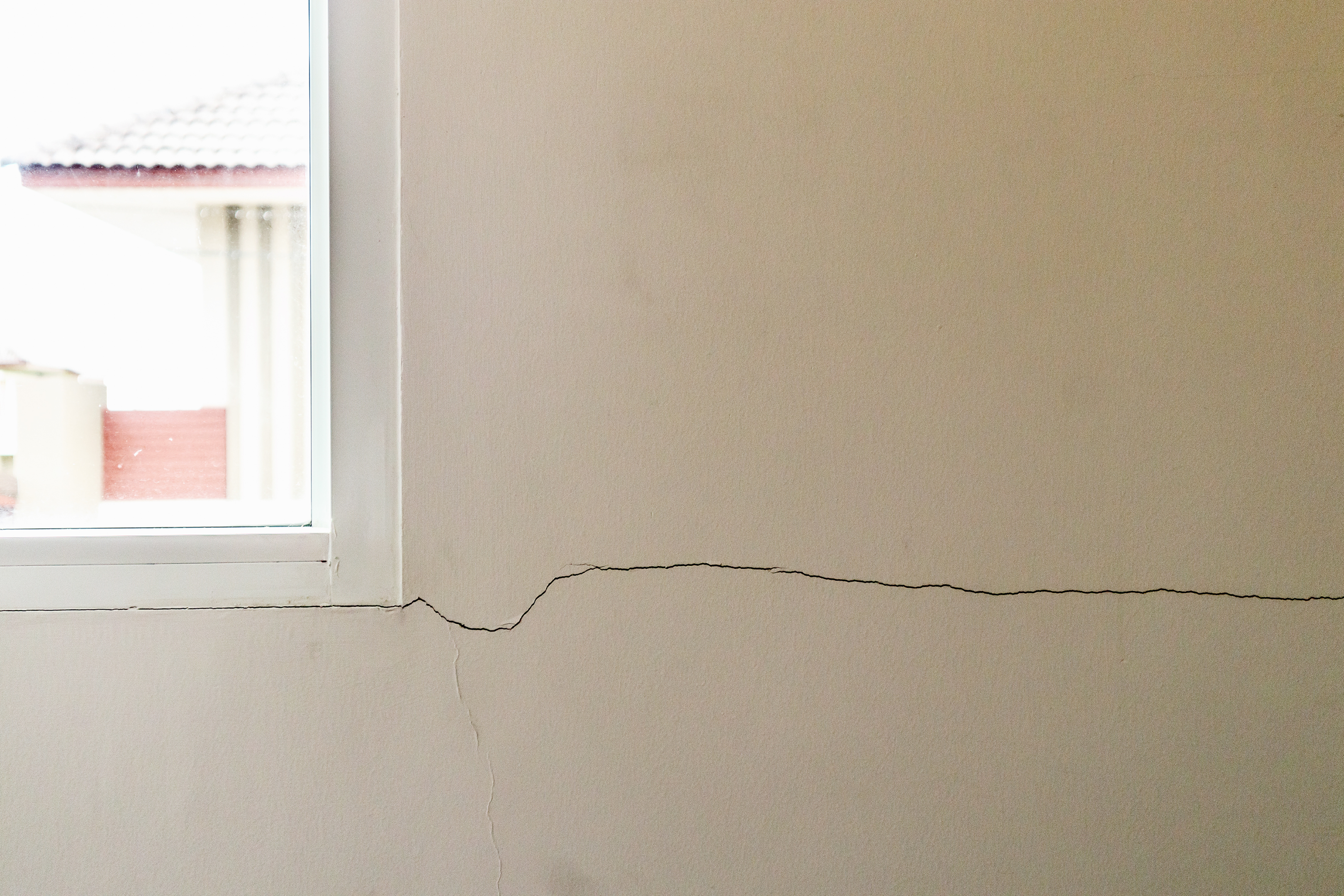 Crack in wall near window because of basement settlement