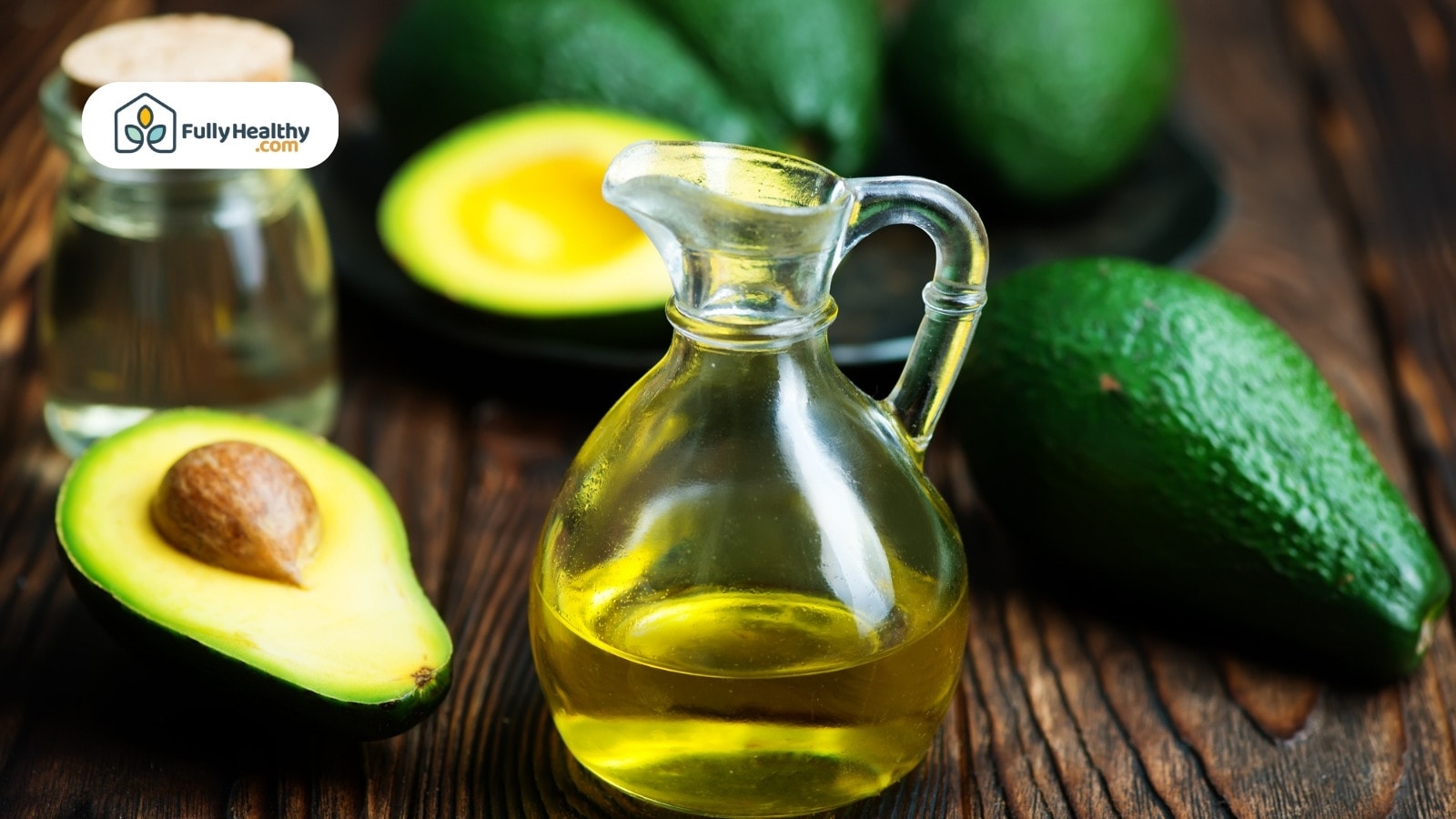 Glass jug of avocado oil with fresh whole and sliced avocados