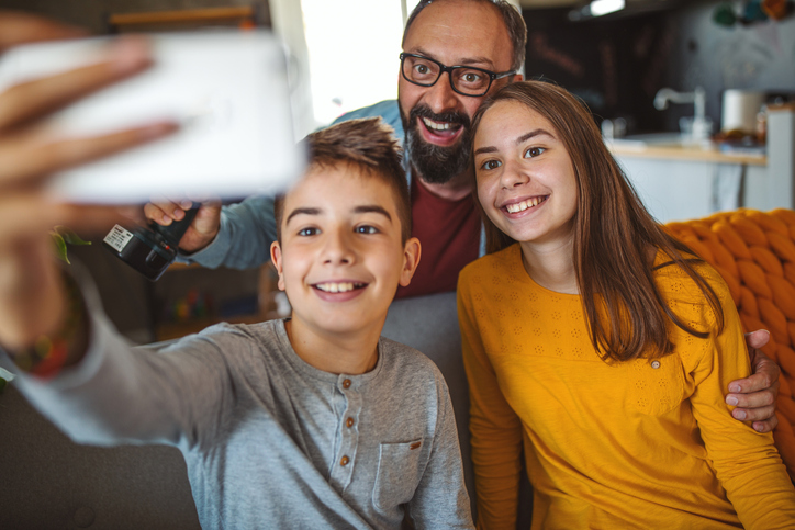 Sweet, smiling family of three snapping a selfie on the sofa. 