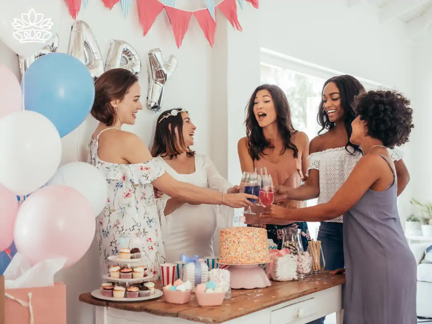 Group of women celebrating a baby shower, gathered around a decorated table with cakes, flowers, and balloons, sharing a joyful moment. Fabulous Flowers and Gifts: Baby Shower Flowers Collection