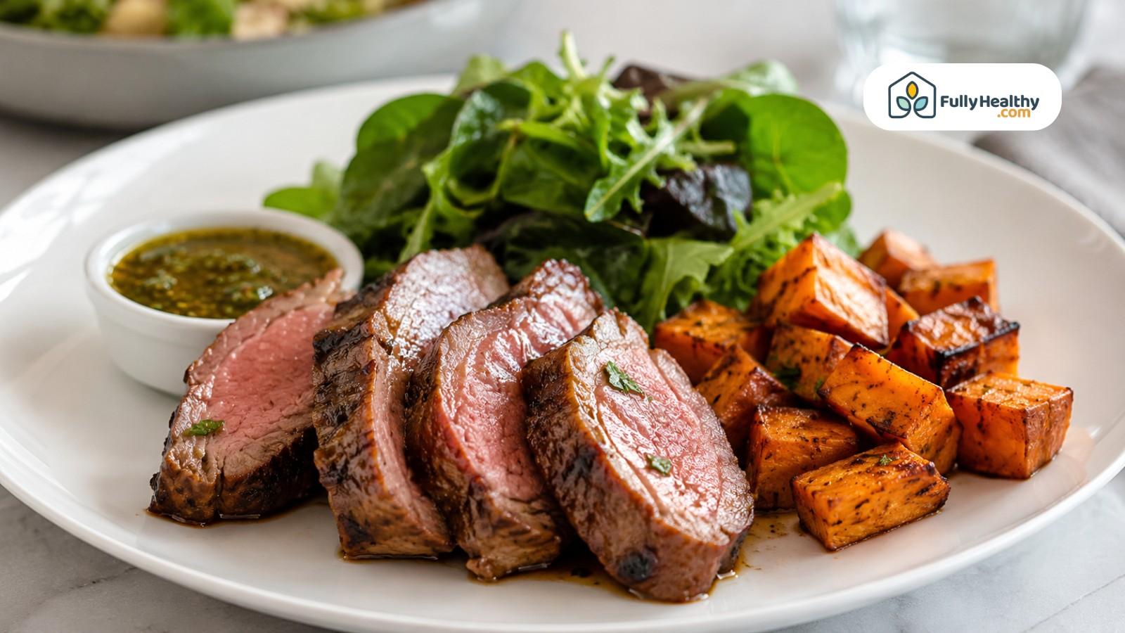 Sliced cooked lamb with sweet potatoes, greens, and herb sauce on plate
