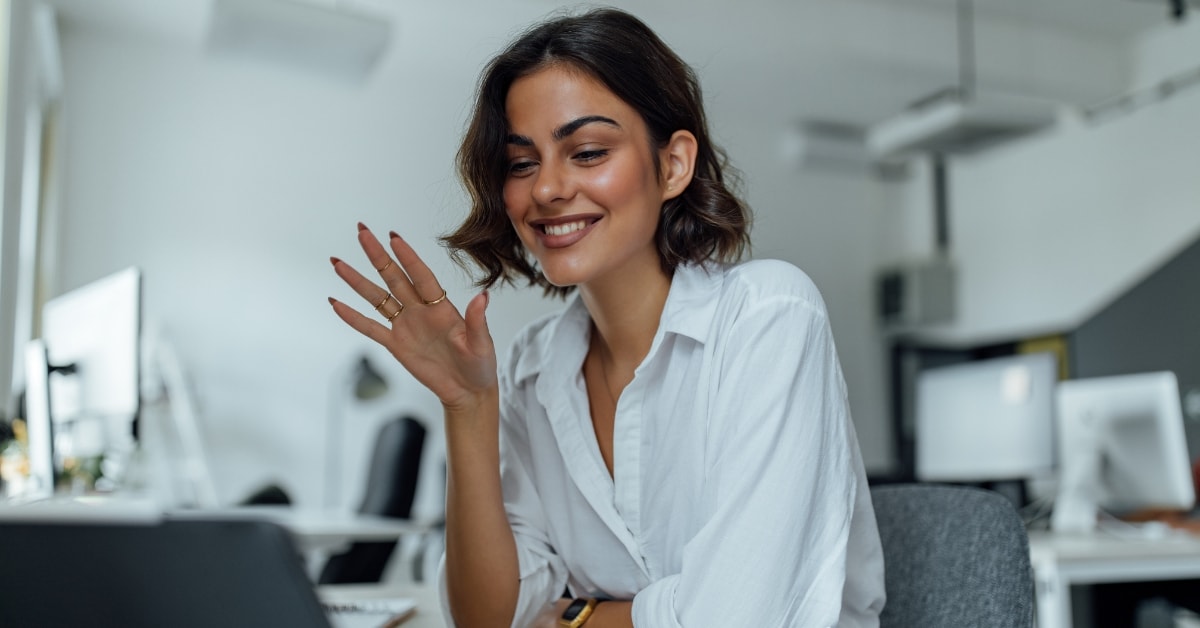 Woman smiling and waving at her laptop during a virtual tax workshop.