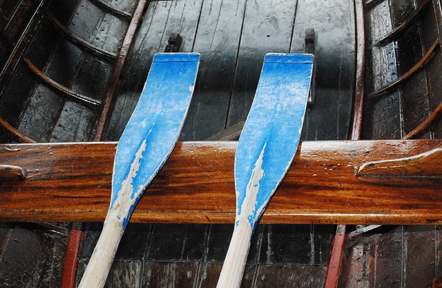 Weathered row boat oars resting on wooden boat thwart. 