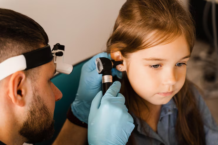Audiologist checking up a child's ear