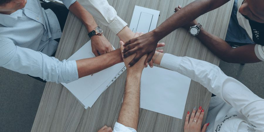 Small business' employees holding hands as a team.