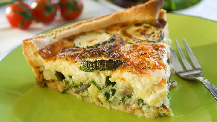 Na imagem: um pedaço de torta de abobrinha em cima de um prato verde.