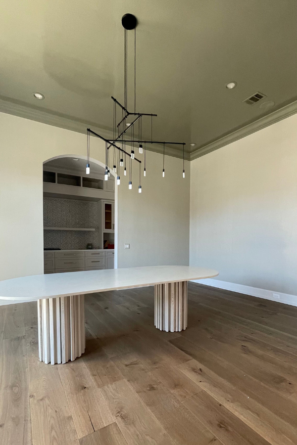 an unfinished dining room with a niche, chandelier, and dining table placed by interior designers