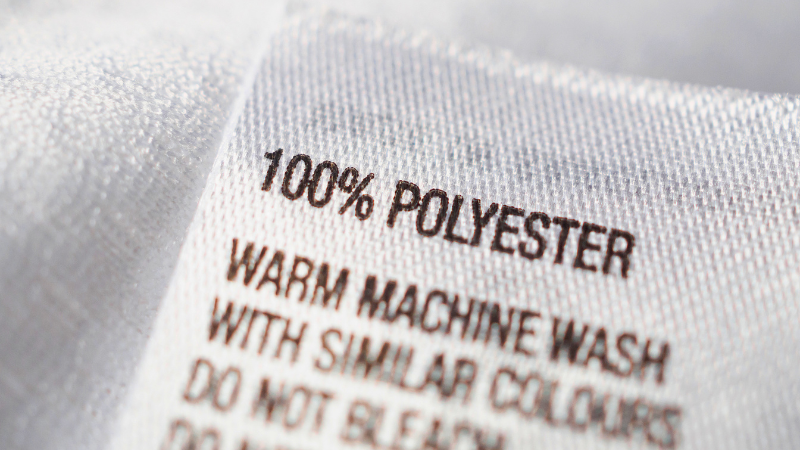 A clothing label reads 100% Polyester, Warm machine wash with similar colours, Do not bleach.