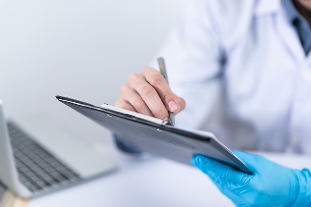 A cropped image of a doctor writing notes on a clipboard.