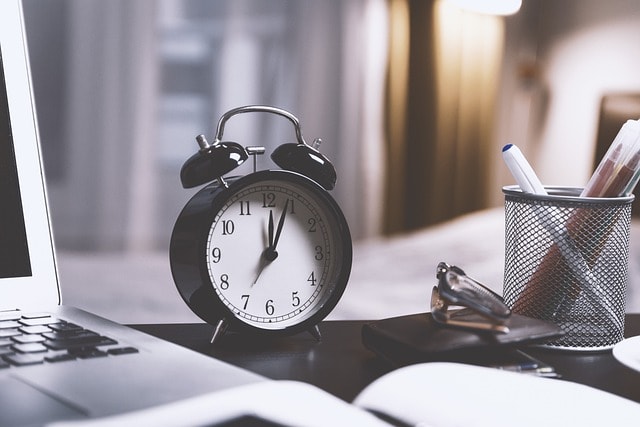 clock next to a laptop symbolizing how you can schedule experiment and split test to boost your search results