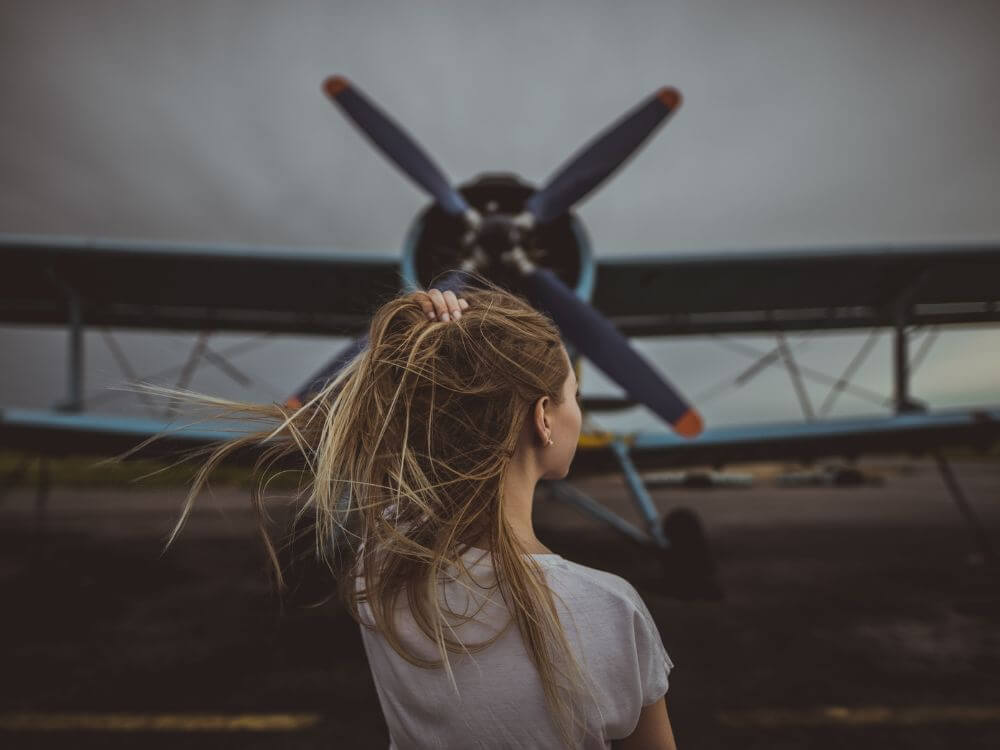 woman running her hands through her hair in front of a plane