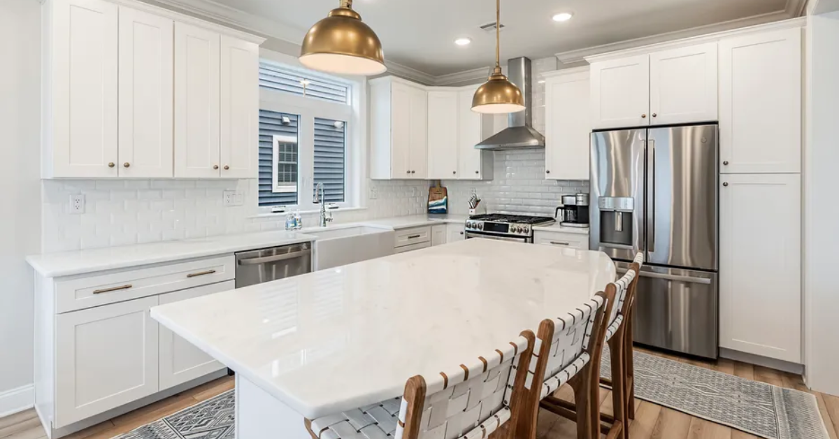 Modern coastal kitchen inside a Jersey Shore vacation rental home featuring white cabinets, large island, and stainless steel appliances.
