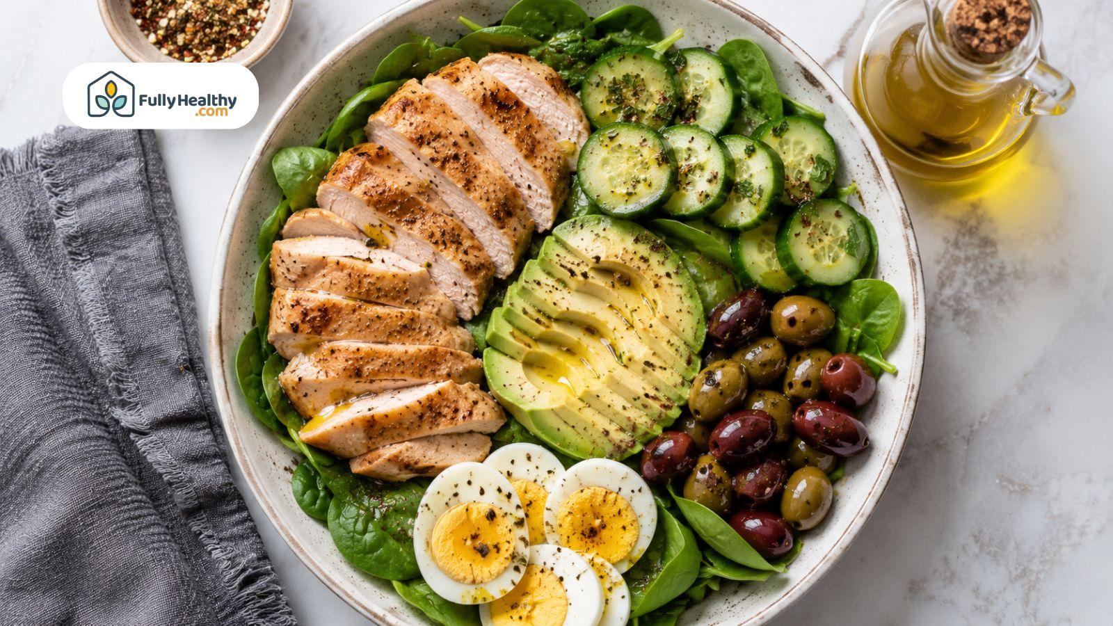 Grilled chicken salad with avocado, eggs, olives, and cucumbers for keto meal.