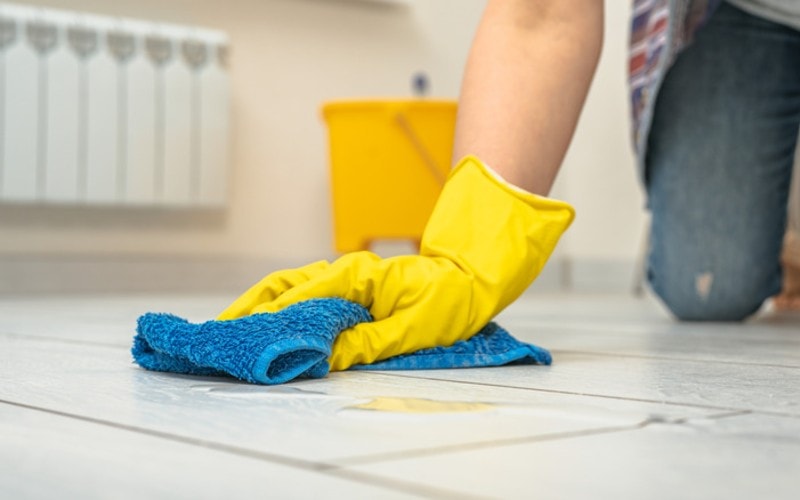 A person scrubs the floor with a microfiber cloth.