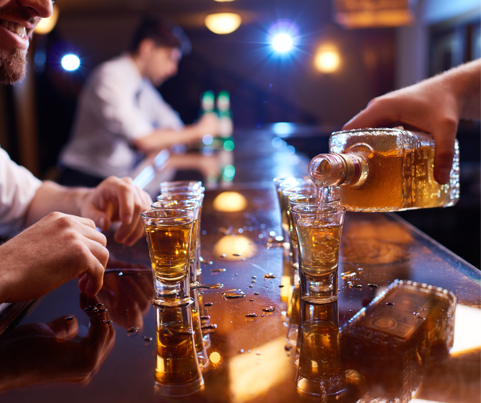 A person pouring a glass of alcohol and looking determined