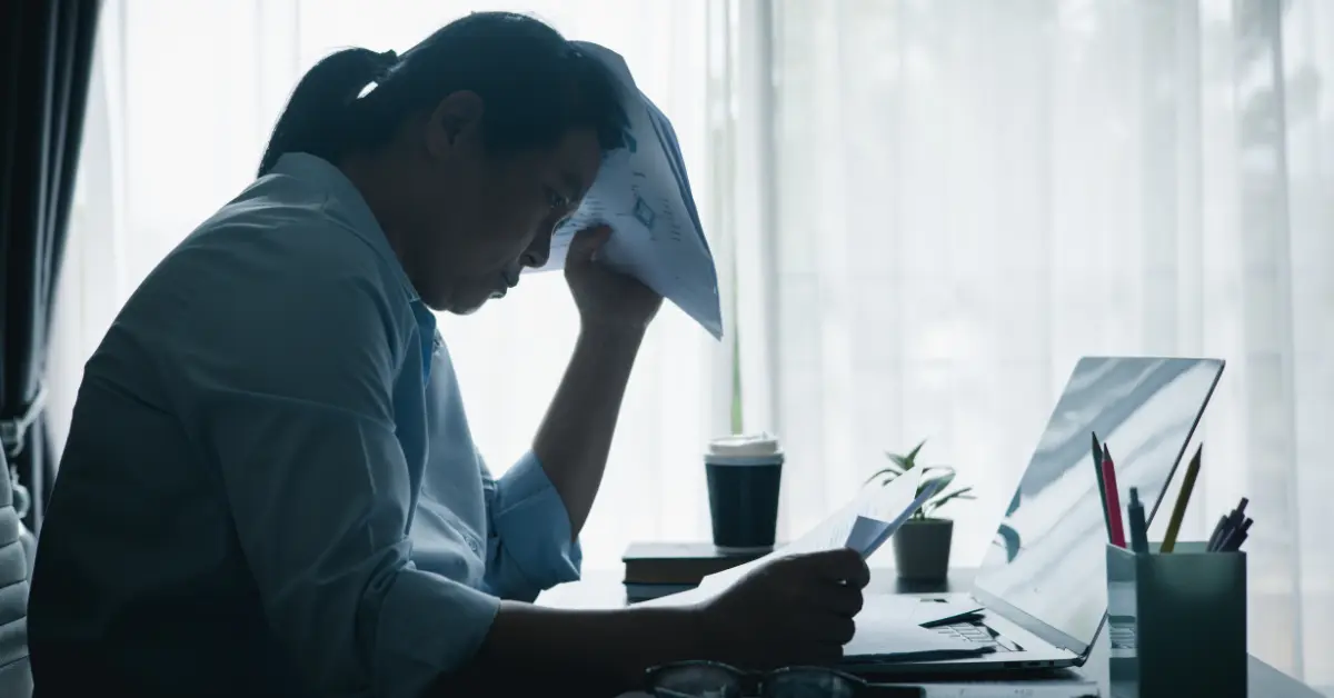 OnlyFans creator working on a laptop and reviewing financial documents while researching can an S corp own an LLC.