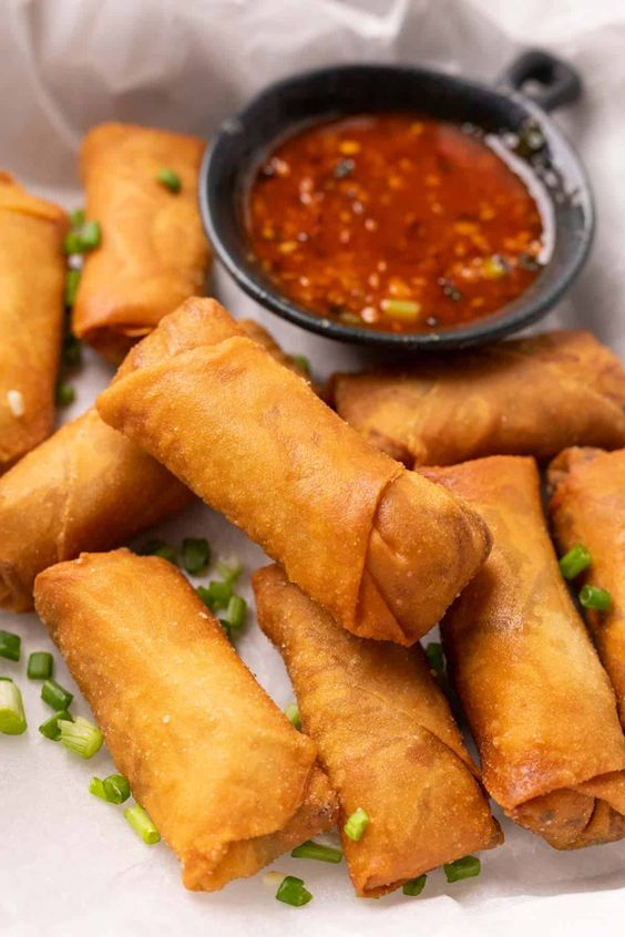 Freshly made spring rolls with vibrant vegetables, served on a white plate.