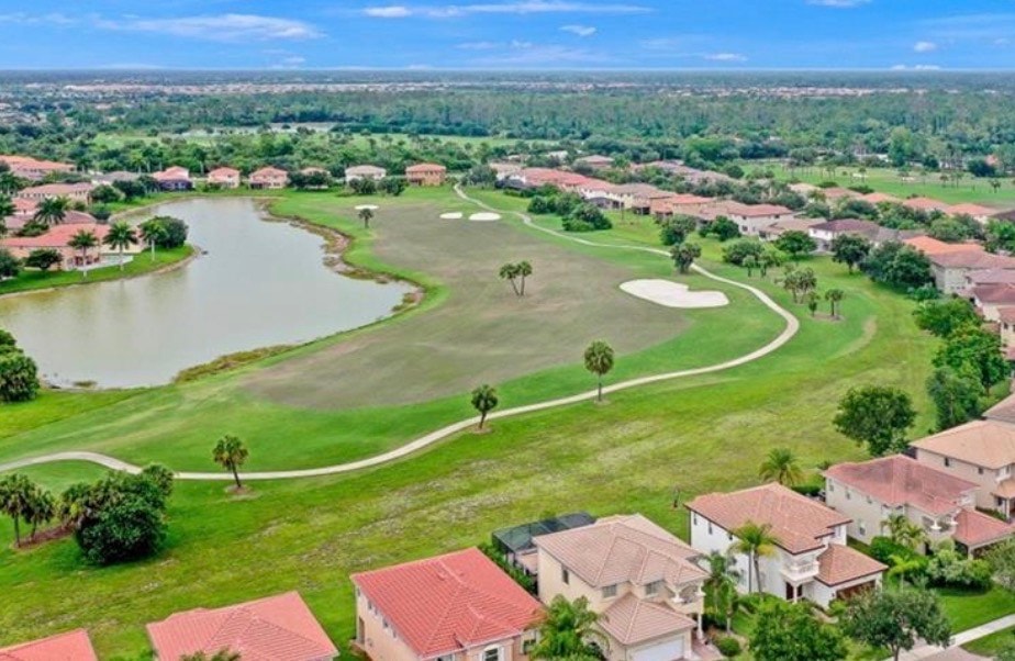 The image depicts a luxurious resort-style pool area surrounded by lounge chairs and a spa, offering a stunning view of a lush golf course. This inviting space is part of the esteemed Valencia Country Club community, ideal for year-round outdoor enjoyment and relaxation.
