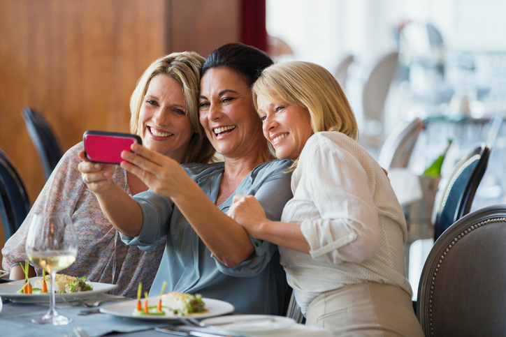Three pretty women snapping a selfie during lunch.