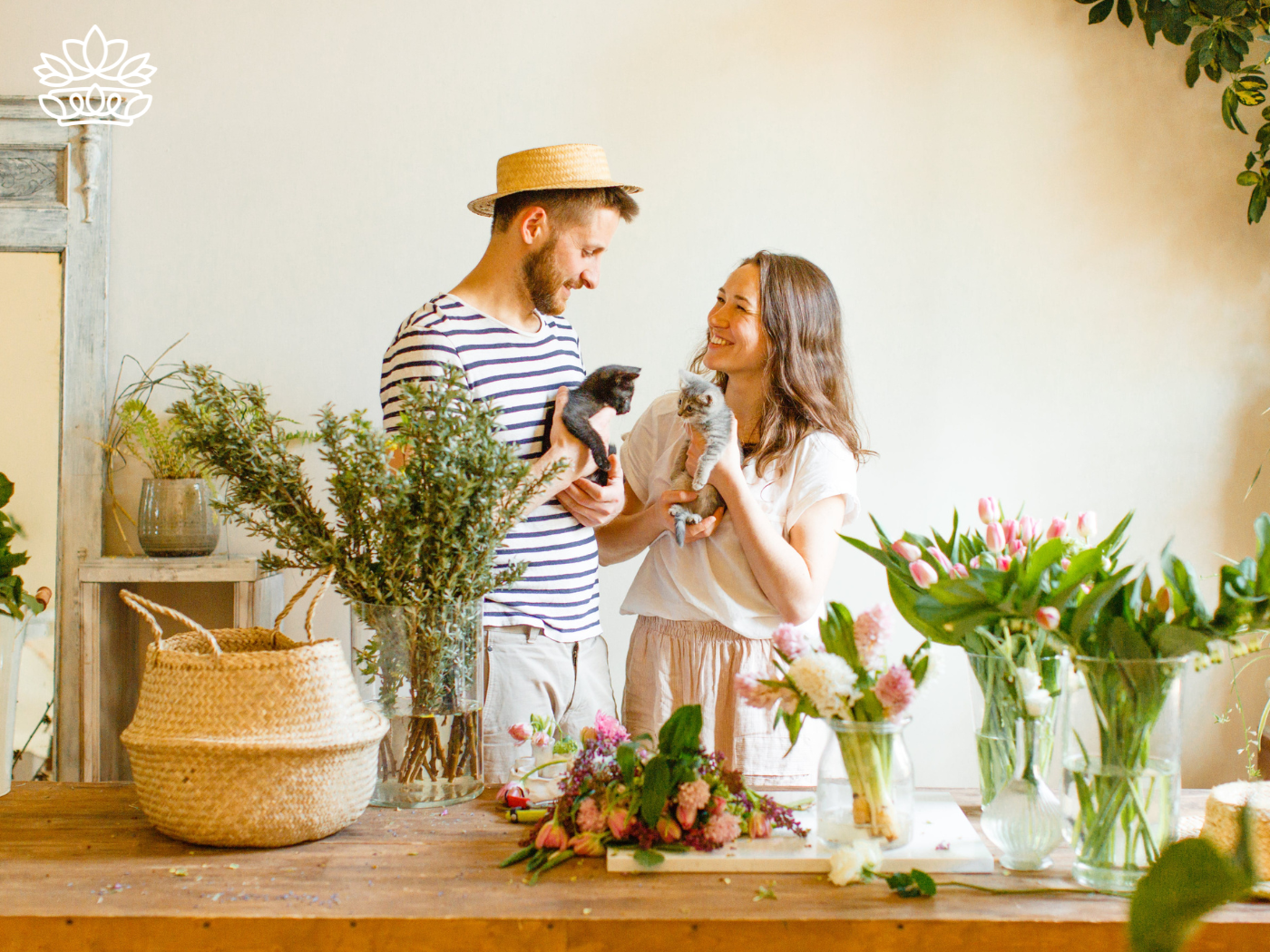 A couple arranging flowers together while holding kittens - Fabulous Flowers and Gifts, All Fabulous Flowers and Gift Boxes.