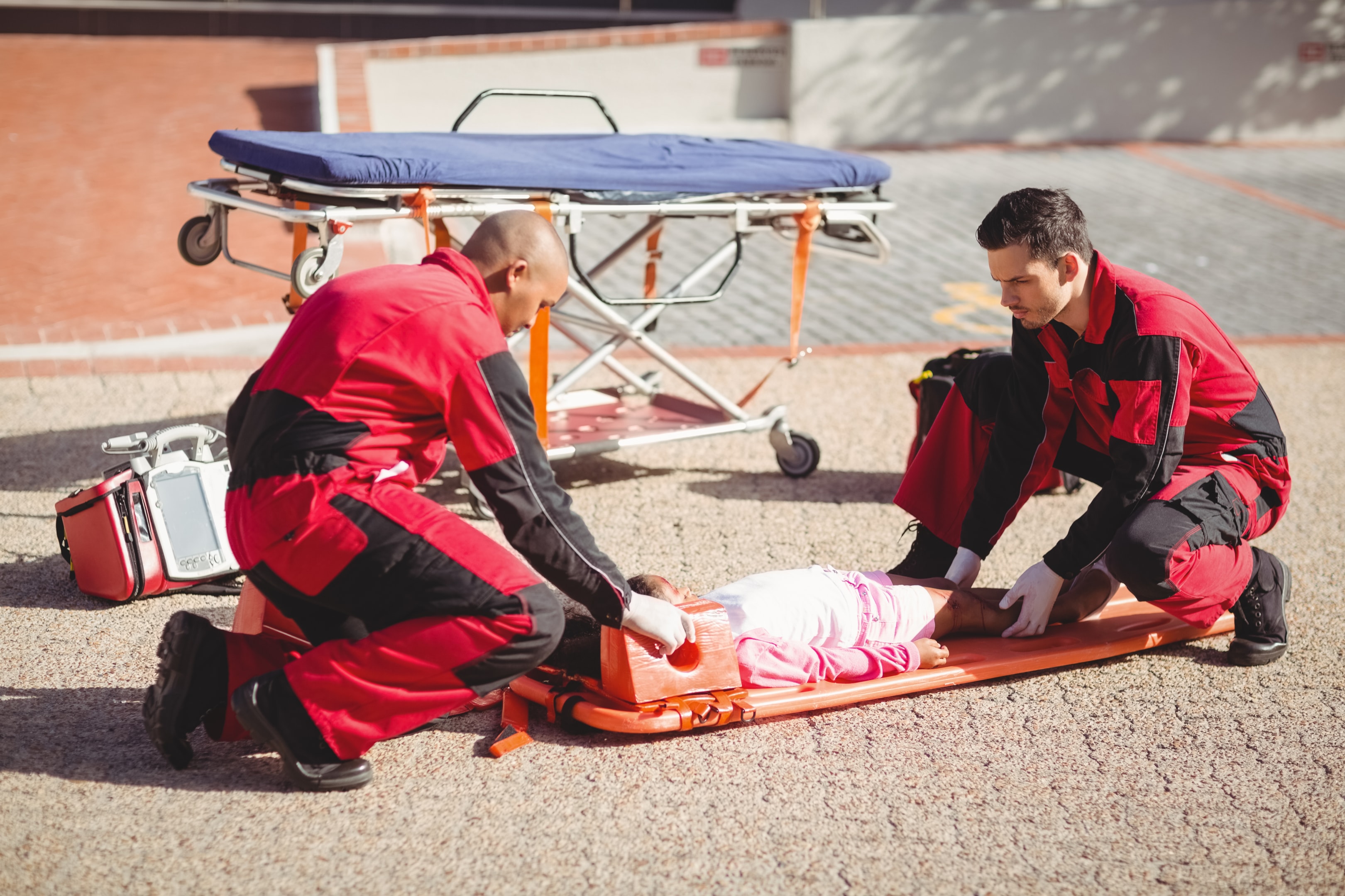 Paramedics putting injured girl onto a backboard to put on stretcher