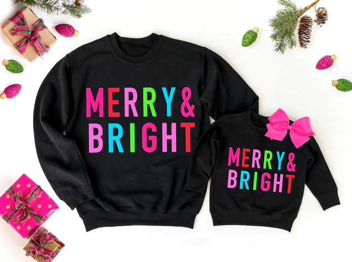 Matching sister outfits in black with colorful block print spelling out "Merry & Bright"